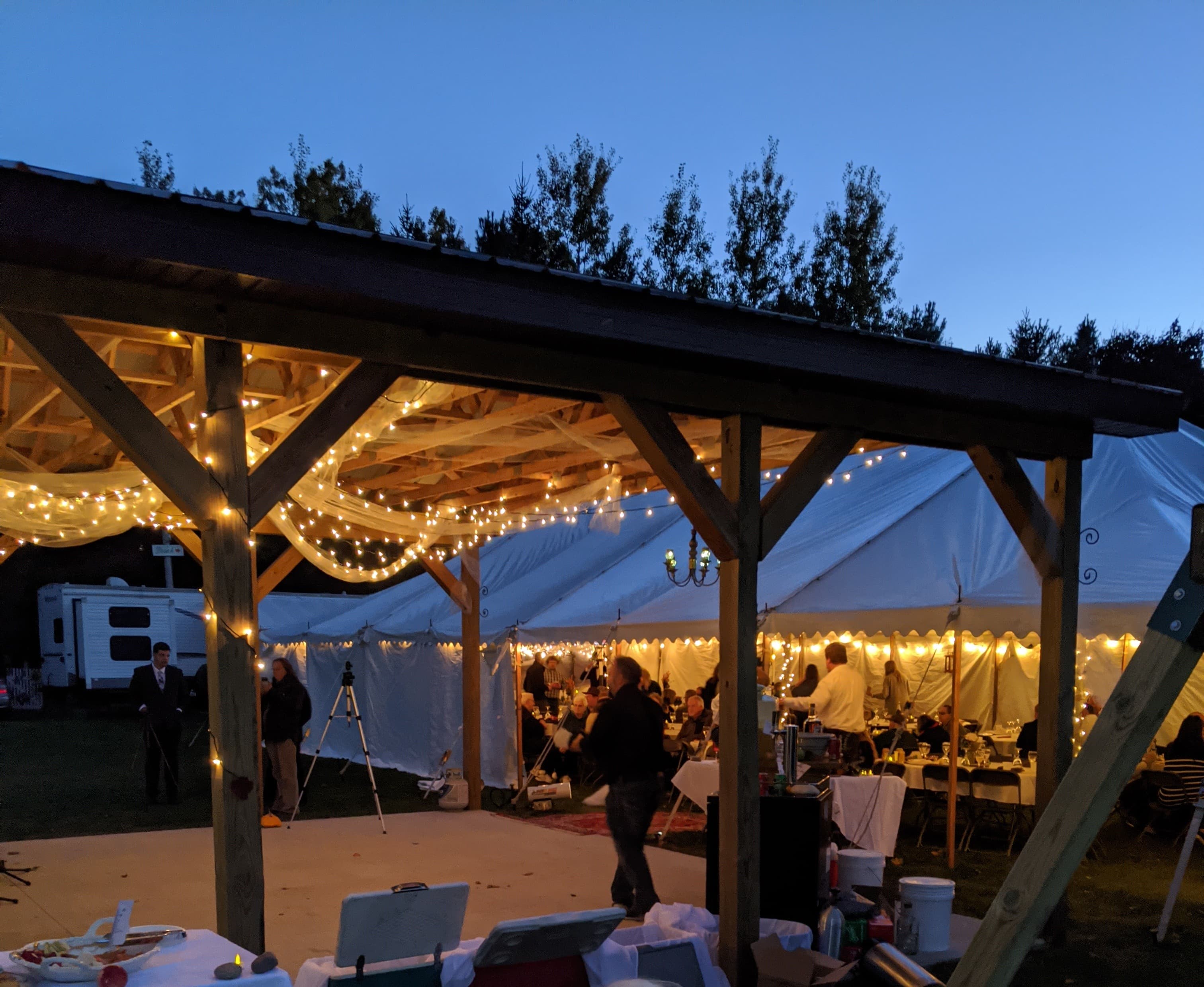 A beautifully lit outdoor event under a tent at dusk.