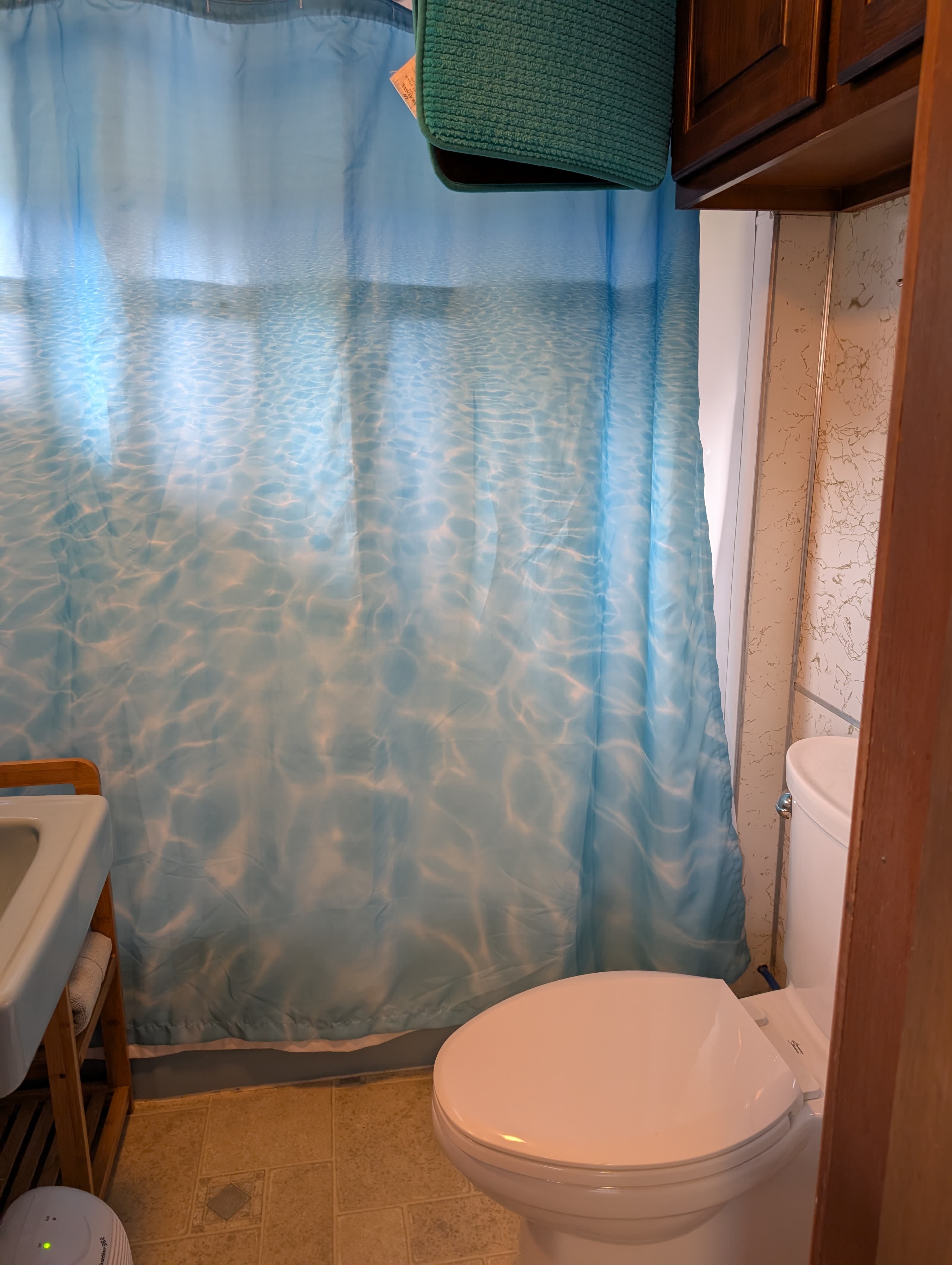 A bathroom featuring a blue shower curtain with a water pattern and a white toilet.