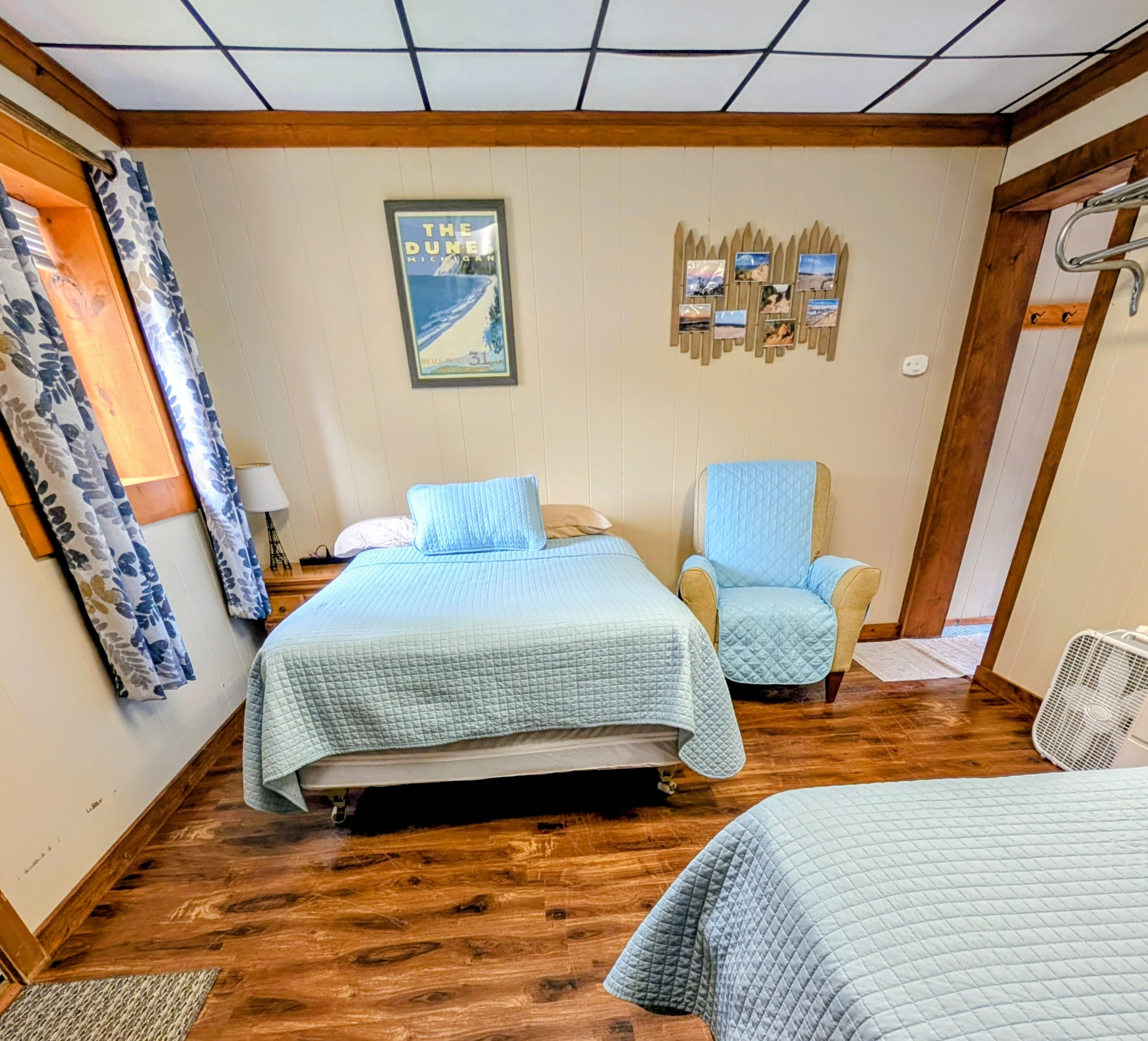 Cozy room with two beds, a blue chair, and rustic decor.