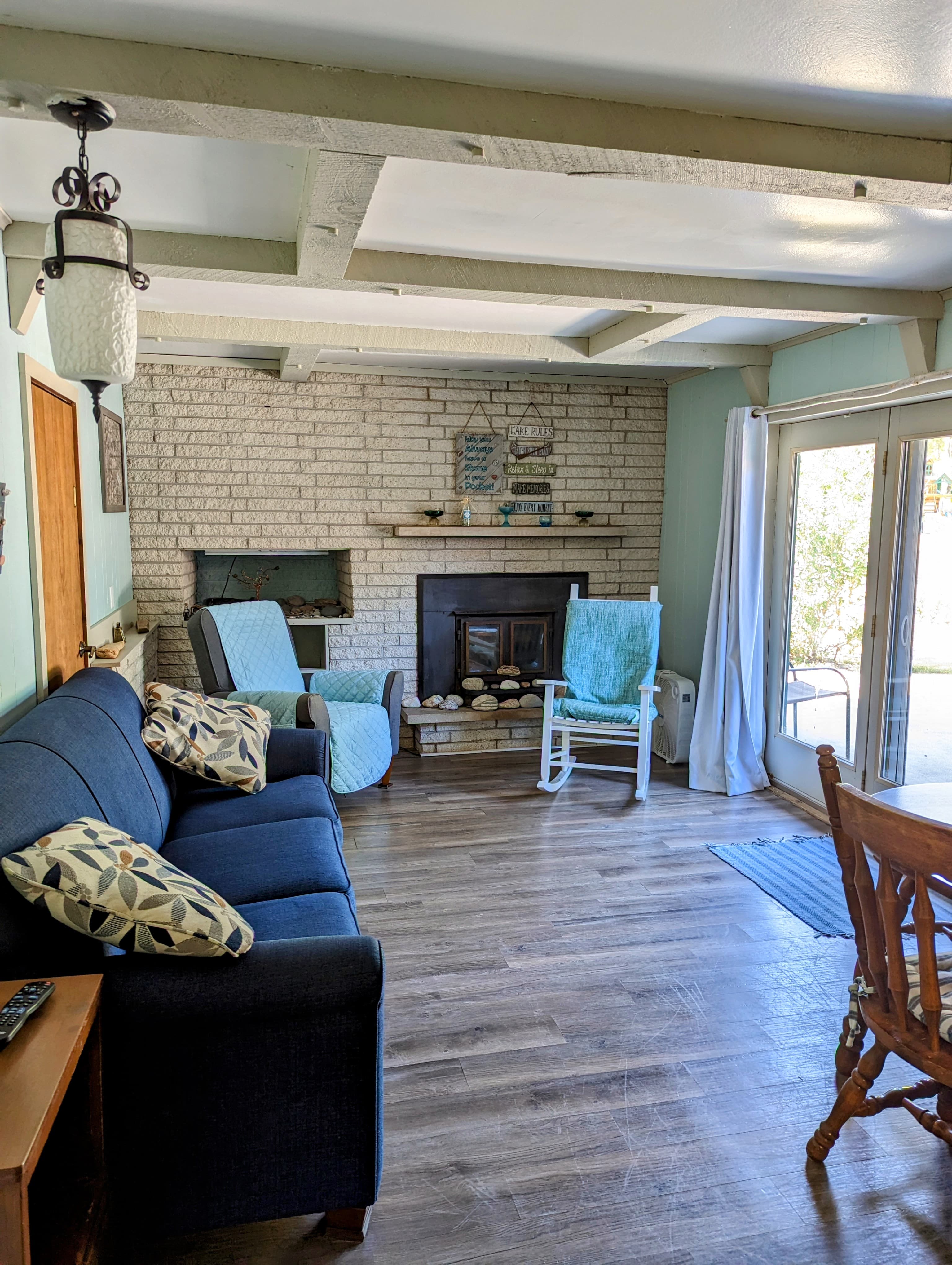 A cozy living room featuring a blue sofa, a fireplace with decorative items, and sliding glass doors leading outside.