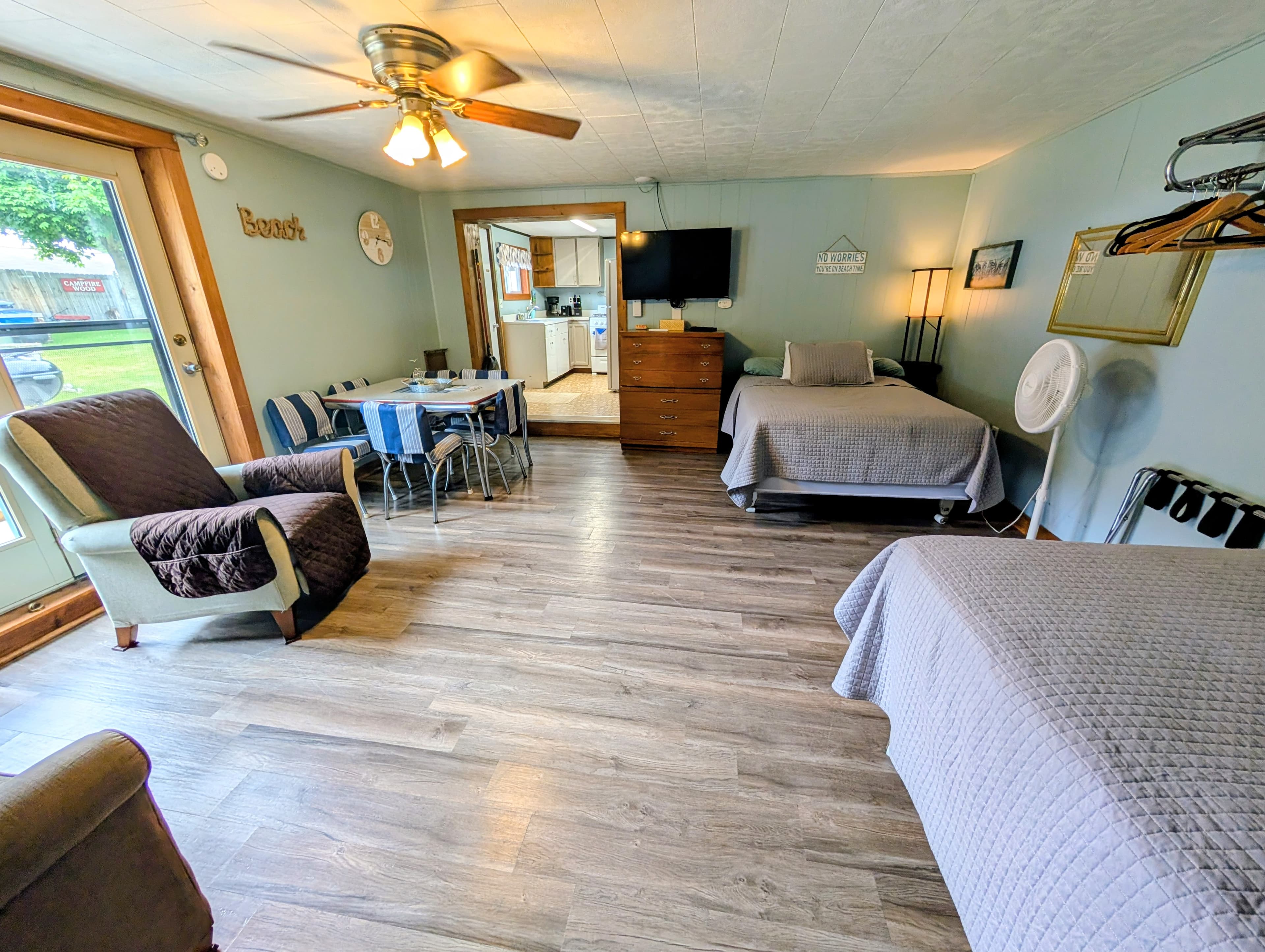 Cozy interior of a rental space featuring two beds, a dining area, and a view of the outdoors.