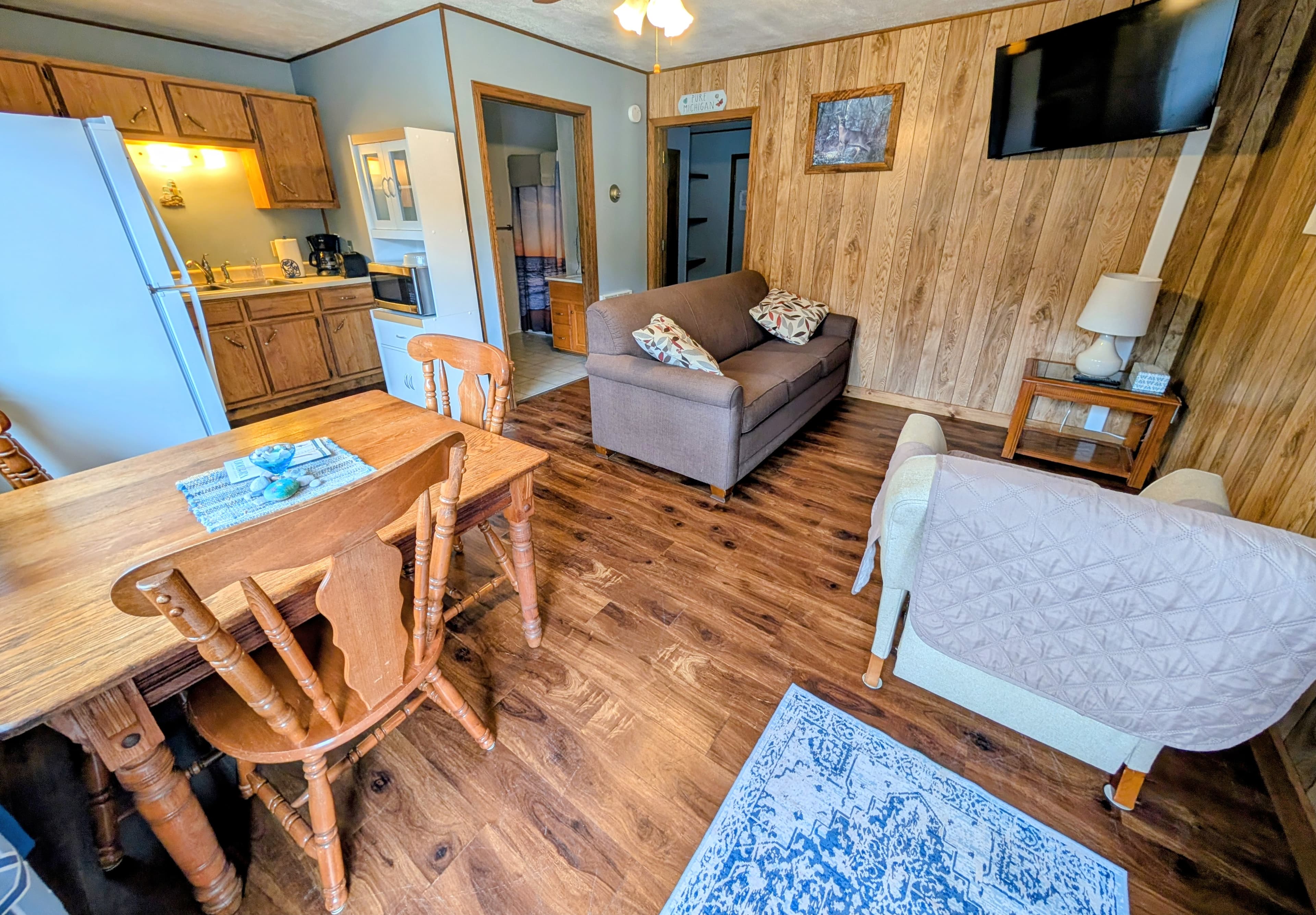 Cozy living space featuring a kitchen, dining area, sofa, and a flat-screen TV.