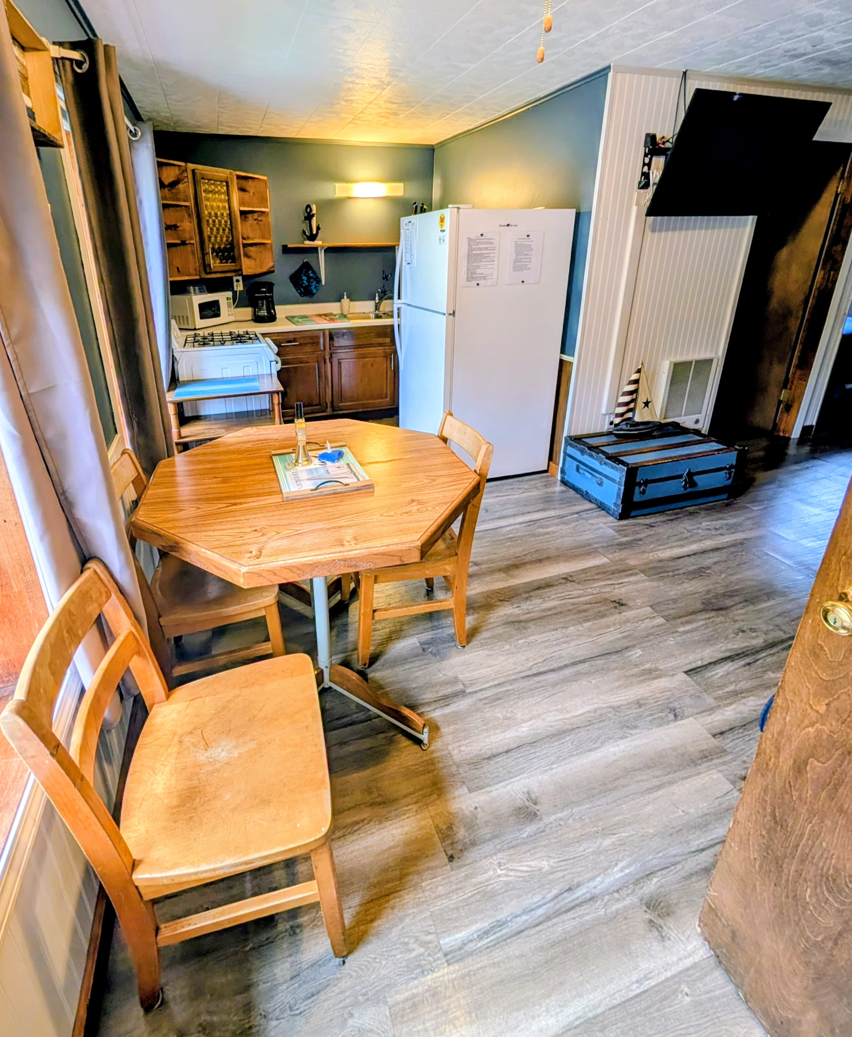 A cozy kitchen with a wooden table, chairs, and essential appliances.