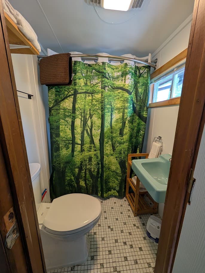 A compact bathroom featuring a nature-themed shower curtain, toilet, and sink area.