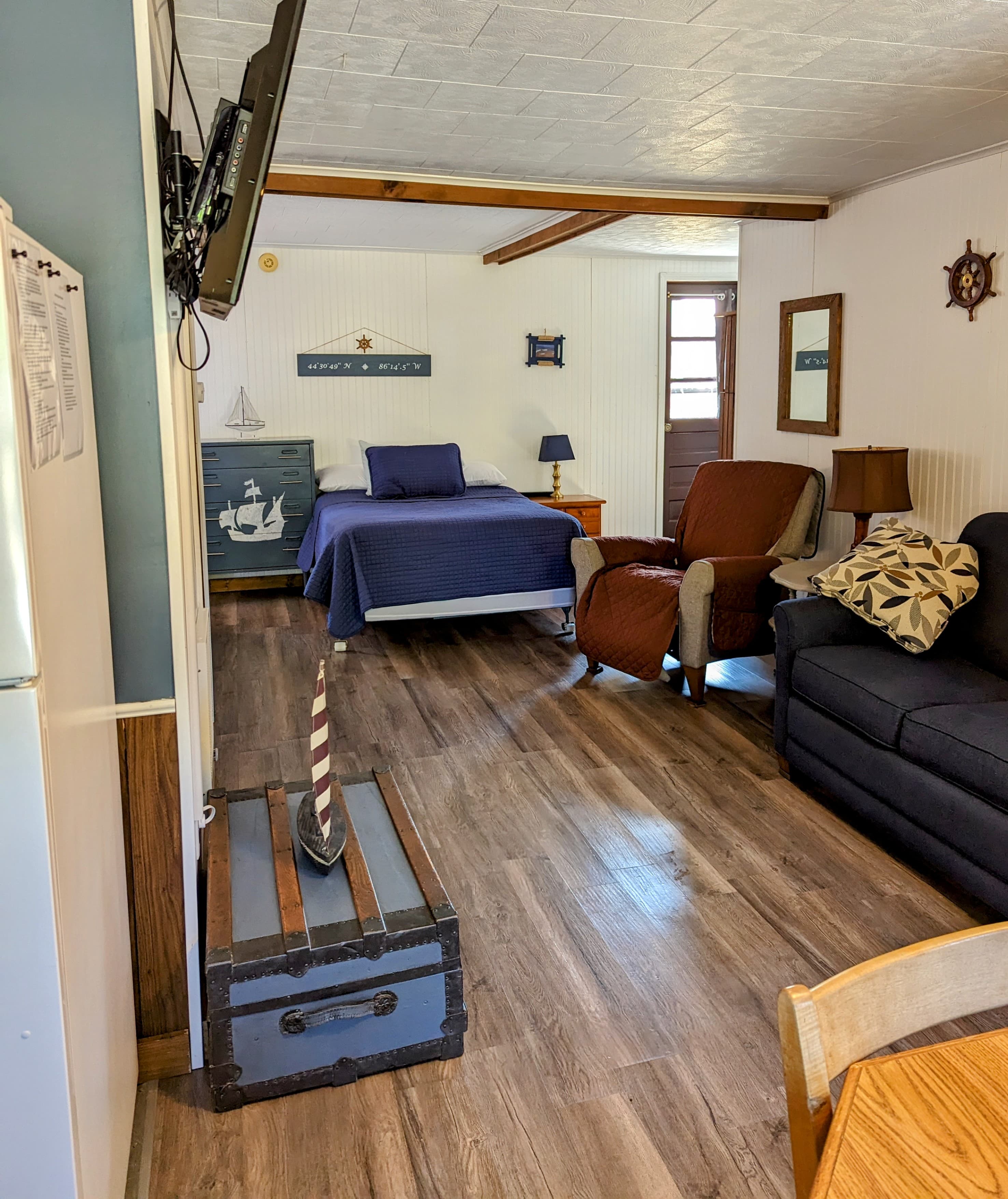 Cozy interior of a rental space featuring a bedroom, living area, and nautical decor.